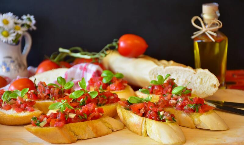 Mehrere Baguettescheiben mit Bruschetta auf Holzbrett