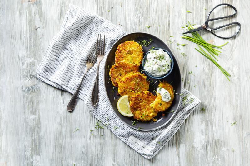 Fünf knusprig ausgebackene Gemüsepuffer auf schwarzem Teller mit Kräuterdip mit dem Thermomix®