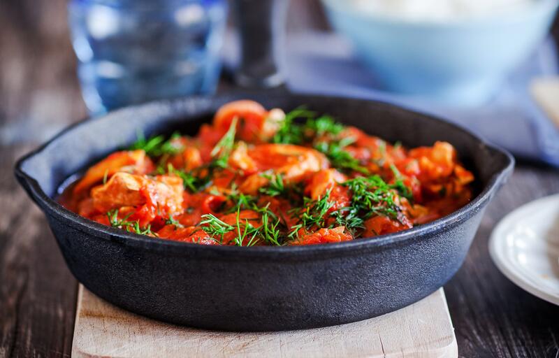 Eine Gussform mit Hähnchen und Paprika mit einer sahnigen Sauce, garniert mit Kräutern.