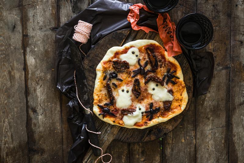 Dekorierte Halloween-Pizza mit Geistern aus Käse und Kapernaugen