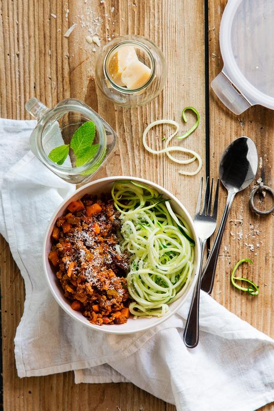 Tiefer weißer Teller mit Zoodles mit Bolognese aus dem Thermomix® auf hellem Holzuntergrund