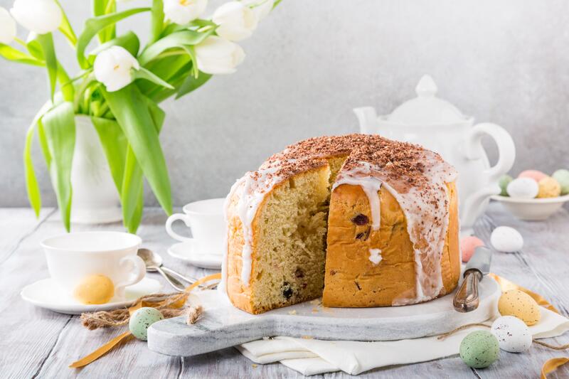 ein Osterbrot angeschnitten, daneben weiße Tulpen und eine Kaffeetasse
