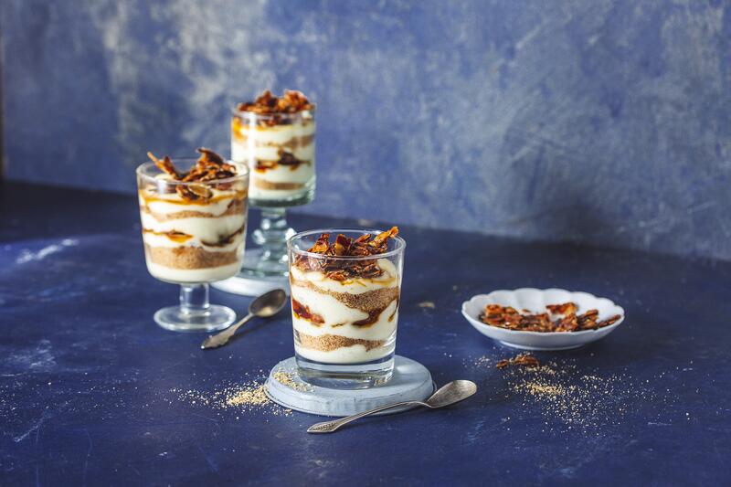 Drei Gläser mit Bienenstich-Dessert aus dem Thermomix® auf blauem Untergrund