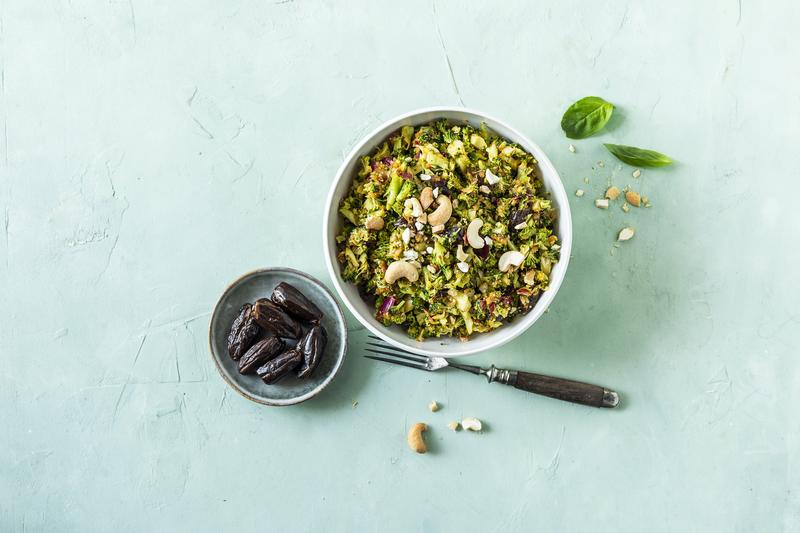 Große weiße Schüssel mit orientalischem Brokkolisalat aus dem Thermomix® mit angestellter kleiner Schale mit Datteln