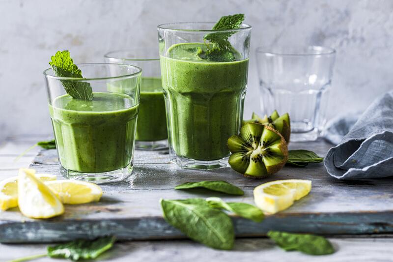 Drei Gläser mit grünem Sommersmoothie aus dem Thermomix® in grauer Welt