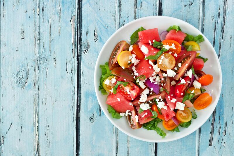 Große weiße Schüssel mit Wassermelonen-Feta-Salat aus dem Thermomix® auf hellblauem Holzuntergrund