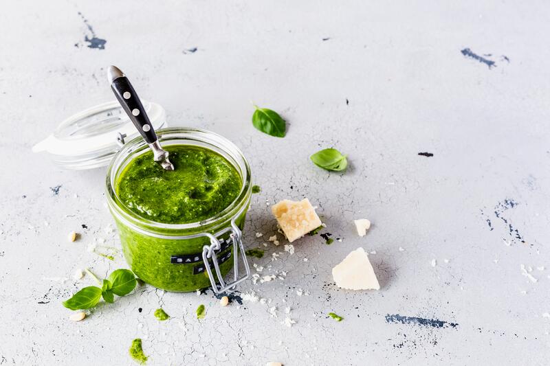 Drei kleine Gläser mit Basilikumpesto aus dem Thermomix® auf hellem Brett 