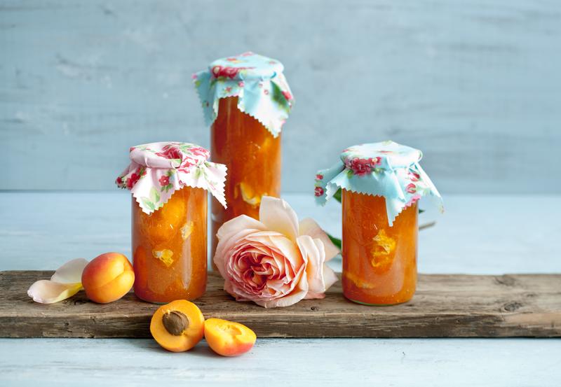 Drei unterschiedliche Marmeladengläser mit Aprikosenkonfitüre aus dem Thermomix® auf Holzbrett