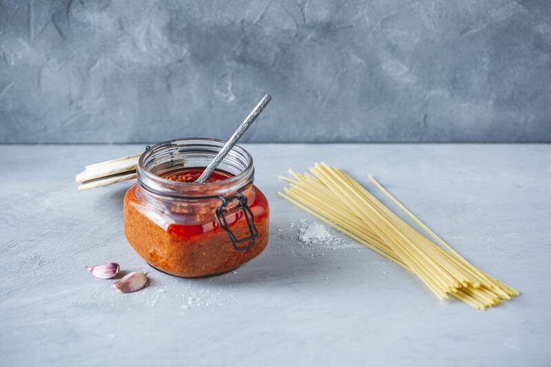 Verschließbares Glas mit Pesto Rosso auf grauem Untergrund