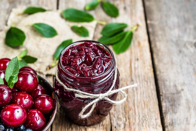 Kirschmarmelade im Glas, danaben frische Kirschen
