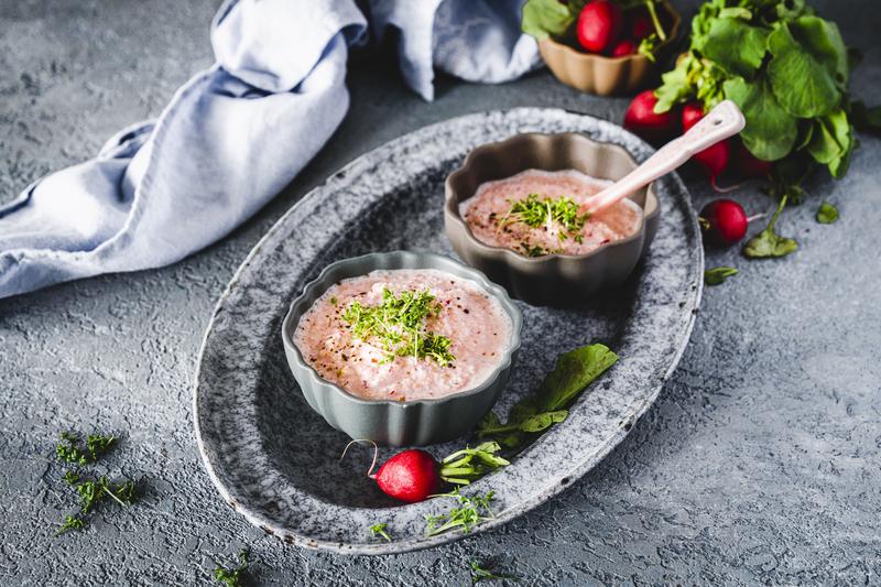 Zwei graue Schälchen mit Radieschendip mit Kressetopping auf grauem Tablett
