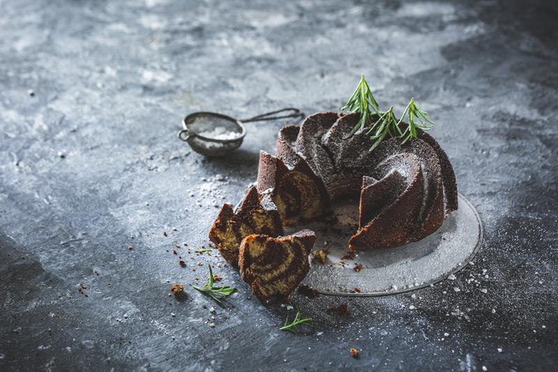 Baileys-Marmokuchen auf grauem Untergrund mit Puderzuckersieb