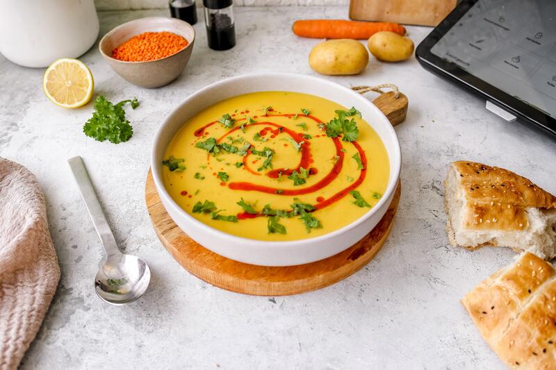 Türkische Linsensuppe mit rotem Topping in einem weißen Teller auf Holztisch