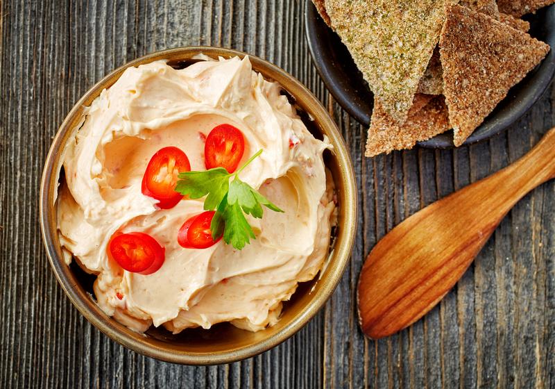 Holzschale mit Mozzarella-Dip mit halbieren kleinen Tomaten und angestellten Tortillachips