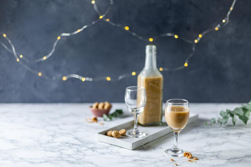 Schnapsglas und -flasche mit Amarettini-Likör auf weihnachtlich gedecktem Tisch