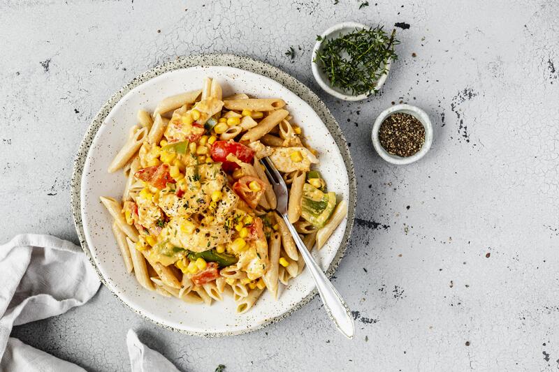 Weißer Teller mit Nudeln und Hähnchen in Paprika-Mais-Soße