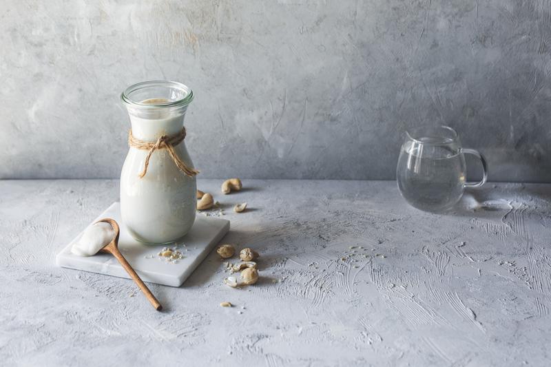 Glasflasche mit Sahne auf grauem Untergrund