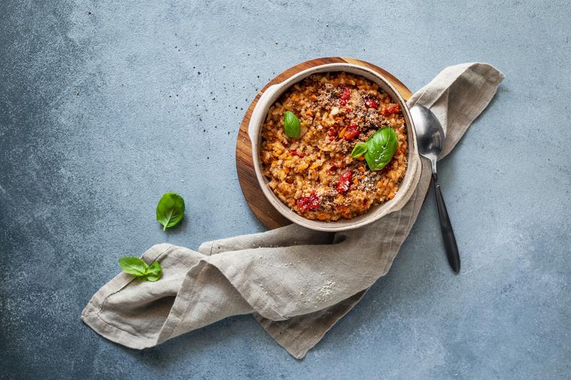 Große Schüssel mit Risotto-Bolognese auf blauem Untergrund