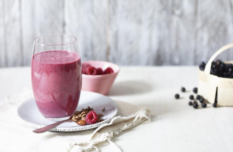 Smoothie in einem Glas mit Himbeeren in einer Schale