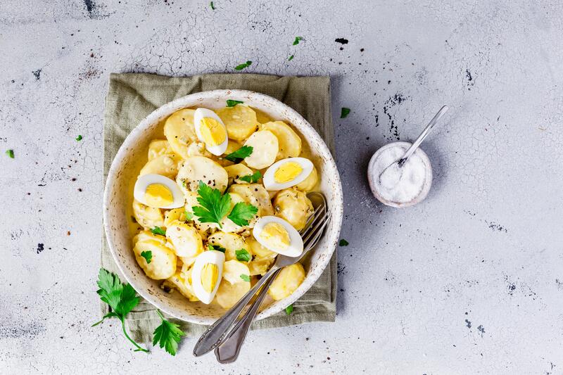 Weiße Schüssel mit Kartoffelsalat mit Mayonnaise und gekochten Eiern