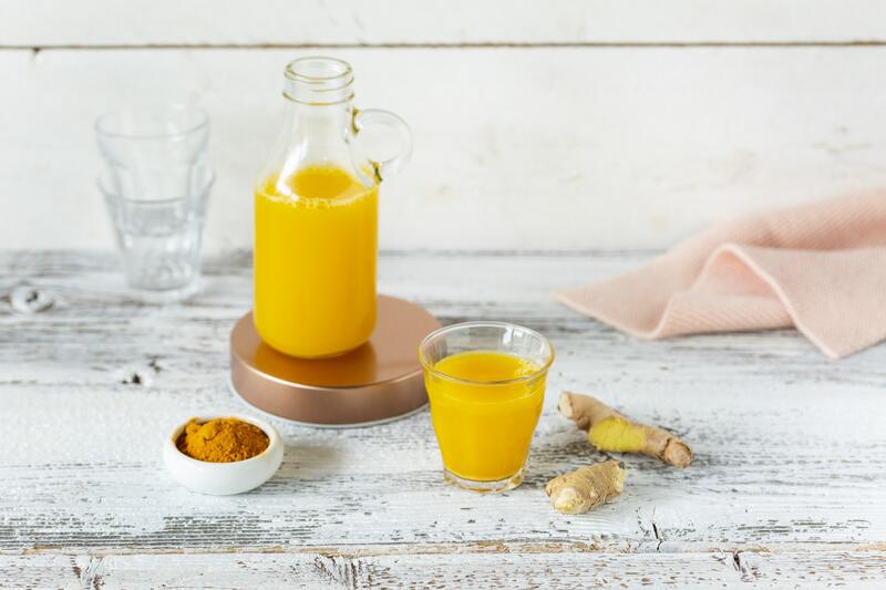 Flasche und Shotglas mit Ingwer-Powershot auf hellem Untergrund