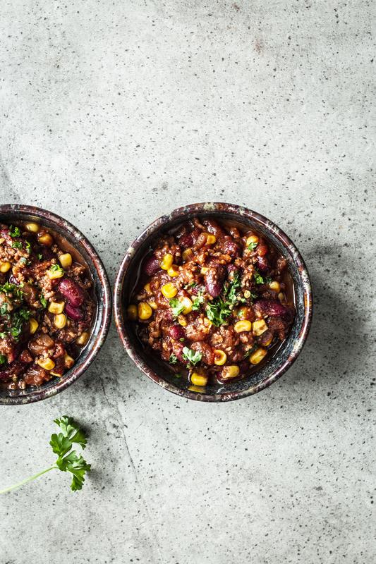 Zwei Schälchen mit Chili con Carne auf grauem Tisch