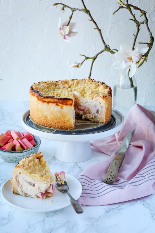 Angeschnittener Rhabarber-Käsekuchen mit angestelltem Teller mit Kuchenstück