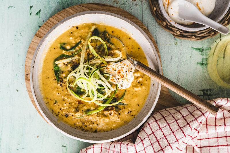 Tiefer Teller mit orangefarbener Suppe mit Zucchini