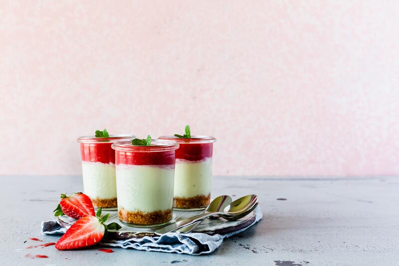 Drei Gläser mit Cheesecake im Glas mit Erdbeersoße