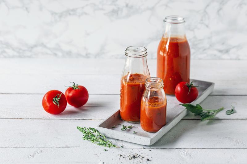 Flaschen mit Tomatensauce auf einem Brett