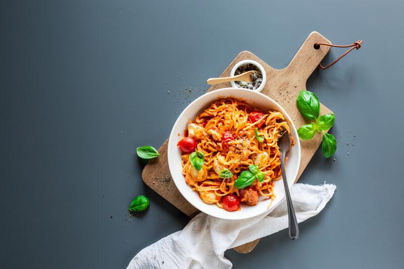 Spaghetti Tomate-Mozzarella in tiefem Teller mit Gabel.