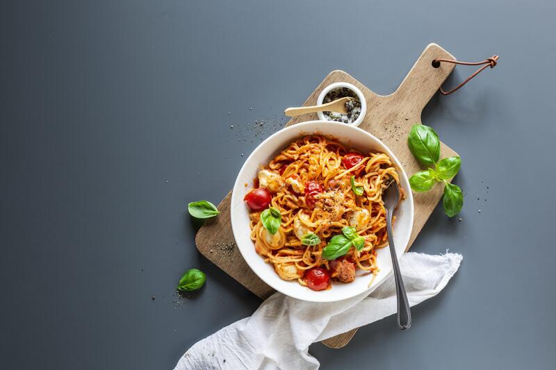 Spaghetti Tomate-Mozzarella in tiefem Teller mit Gabel.