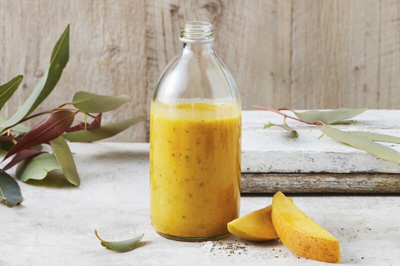 Große Flasche mit Mango-Dressing mit angelegten Mangospalten