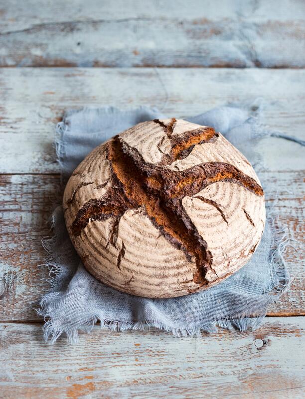 Ganzes Bauernbrot auf blau-grauem Holzuntergrund