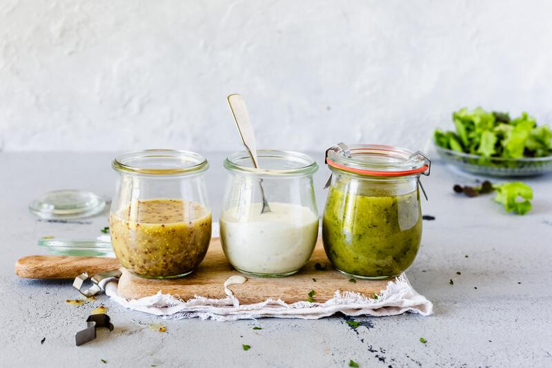 Drei Gläser mit unterschiedlichen Salatdressings