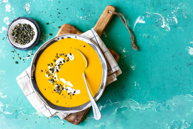 Butternut-Kürbissuppe auf leuchtend-blauem Untergrund