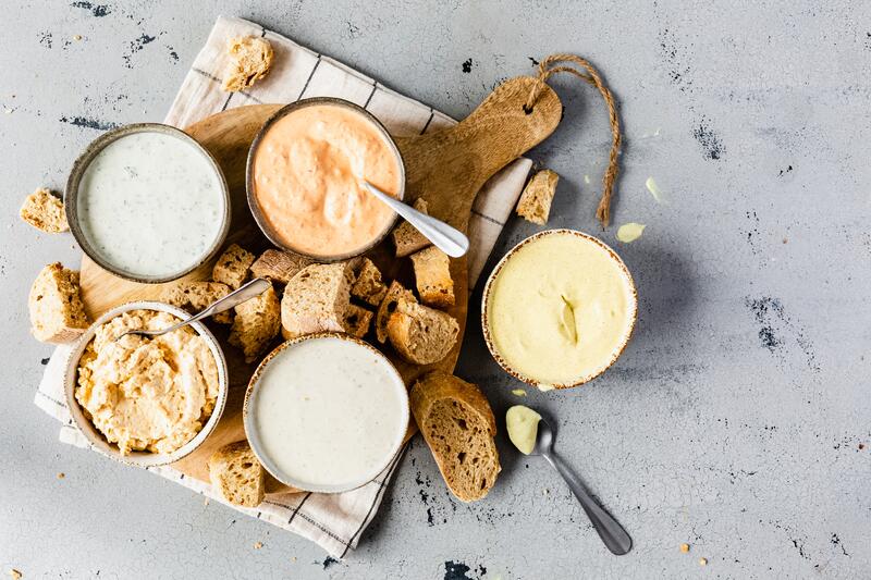 5 unterschiedliche Dips in kleinen Schälchen auf Holzbrett