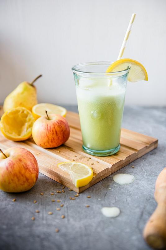 Grüner Saft im Glas mit Apfel und Birne auf Holzbrett