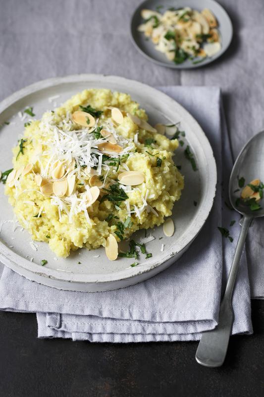 Teller mit Blumenkohlrisotto und gehobelten Mandeln, darüber Petersilie und Parmesan