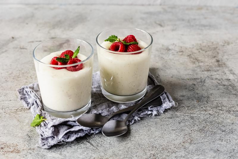 Vanillecreme in zwei Gläsern mit Beeren garniert.