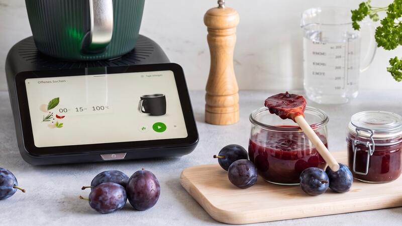 Der Thermomix® TM7, davor liegen Pflaumen und stehen Gläser mit Pflaumenkonfitüre