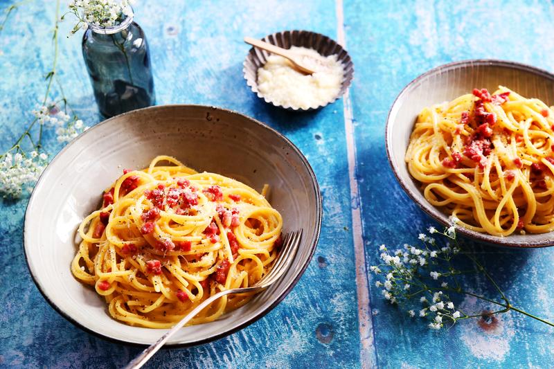 Spaghetti Carbonara in tiefem Pastateller auf blauem Untergrund