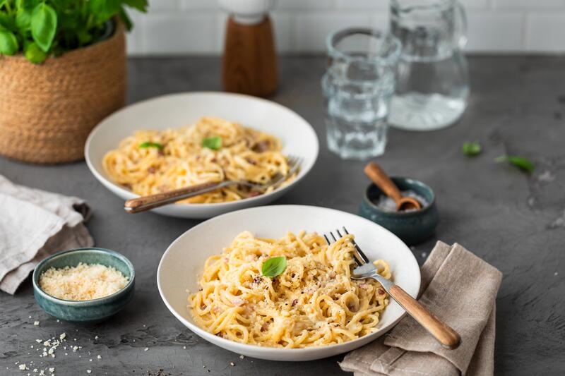 Spaghetti Carbonara in tiefem Pastateller auf blauem Untergrund