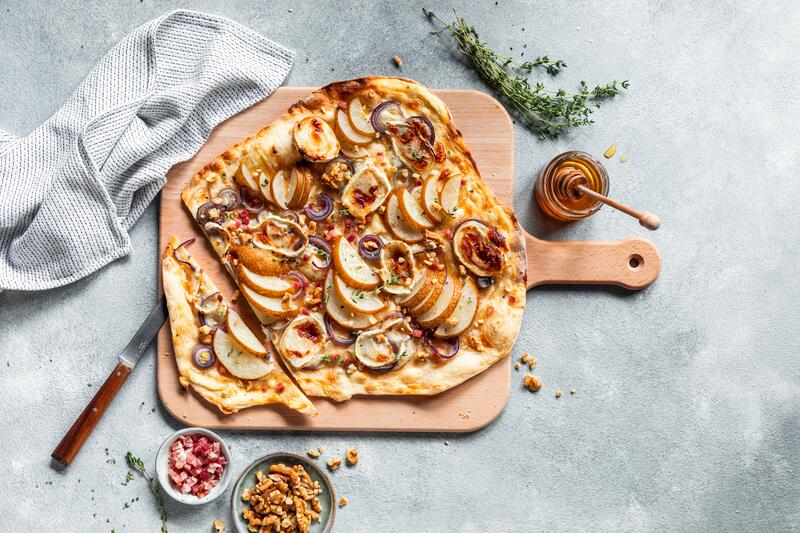 Französischer Flammkuchen mit Birne auf Holzbrett
