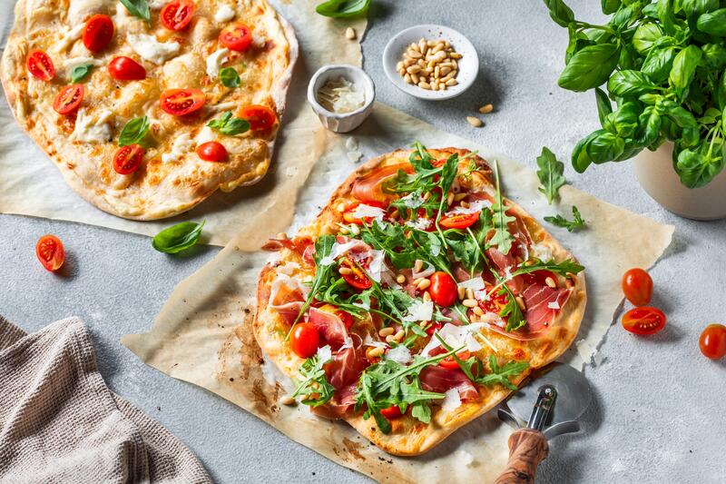 Italienischer Flammkuchen mit Schinken, Tomaten und Rucola