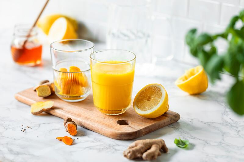 Glas mit aufgelösten Ingwer-Shot-Eiswürfel auf Holzbrett
