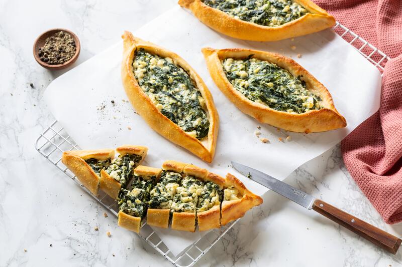 Kalorienarme Skyr-Pide mit Spinat und Feta auf weißem Backpapier