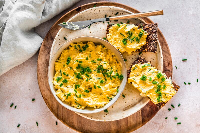 Low-Carb-Eiercreme-Brotaufstrich in Schüssel auf Teller mit beschmierten Broten