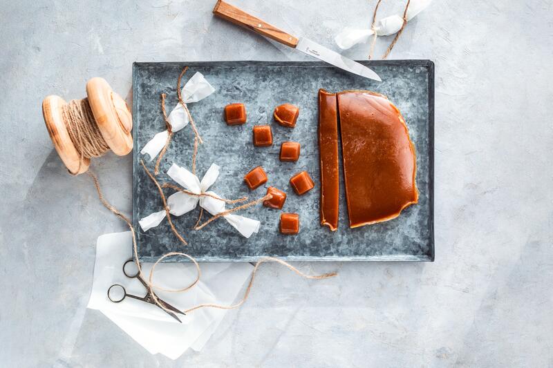 Selbst gemachte Karamellbonbons auf einem Blech mit Karamellblock und Kordel.