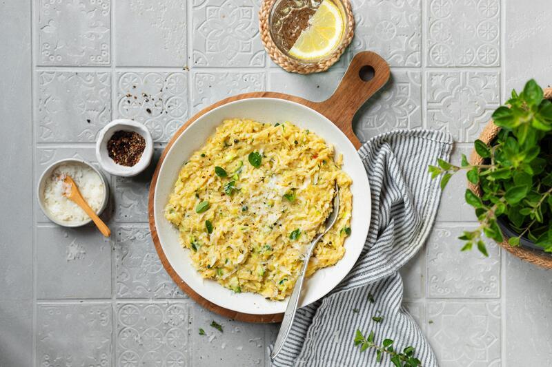 Zucchini-Orzotto in tiefem Teller auf Holzbrett